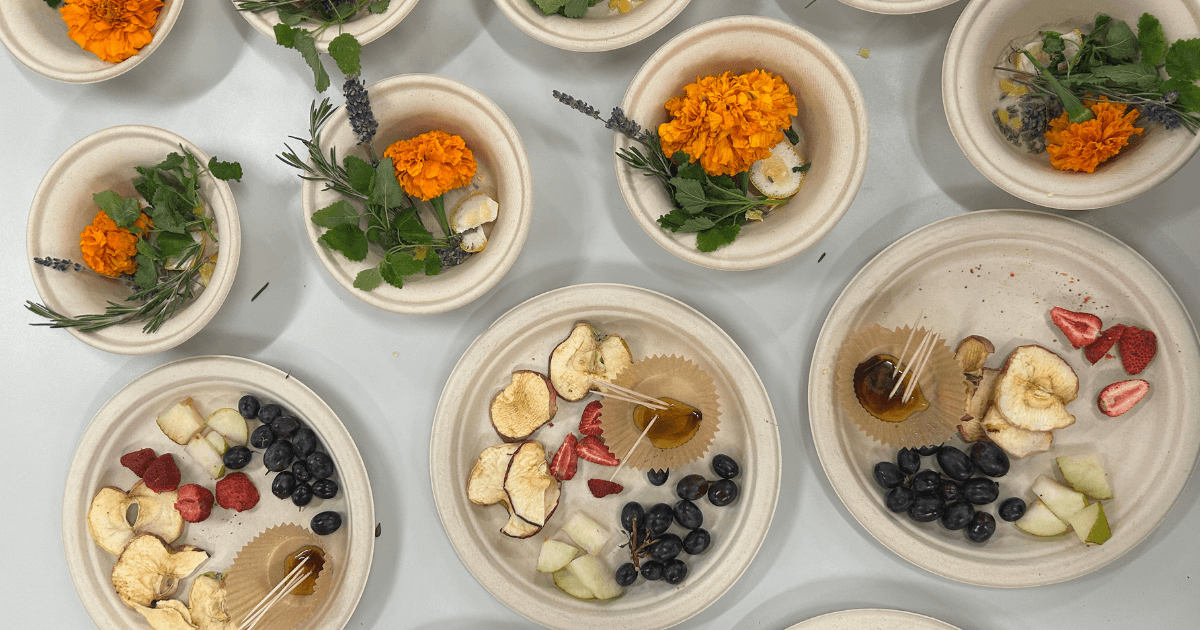 bowls and plates filled with rosemary, lavender, lemon balm, strawberries, grapes, honey, apple slices, marigolds and pears